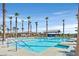 Community pool with palm trees, sun loungers, and a covered seating area under a clear blue sky at 2383 Elmont Ave, North Las Vegas, NV 89086