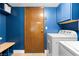 Well organized laundry room with front loading washer/dryer, utility sink, storage and wood door at 2425 Greens Ave, Henderson, NV 89014