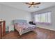 Cozy bedroom with wood flooring, a ceiling fan, and a large window for natural light at 2554 Braehead Ln, Henderson, NV 89044