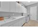 Well-lit laundry room with ample white cabinets, a utility sink, and modern washer and dryer at 2554 Braehead Ln, Henderson, NV 89044