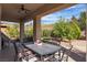 Covered patio area with an outdoor dining set and views of a lush landscaping at 2554 Braehead Ln, Henderson, NV 89044