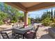 Covered patio featuring an outdoor dining set overlooking the landscaped pool area at 2554 Braehead Ln, Henderson, NV 89044