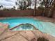 Backyard inground pool with rock border and a built in hot tub and palm trees at 2571 Swans Chance Ave, Henderson, NV 89052