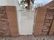 Side yard with a secure white metal gate set in a stone wall, surrounded by pea gravel landscaping at 2571 Swans Chance Ave, Henderson, NV 89052