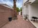 Side yard with palm tree and a white metal shelving unit next to a brick wall at 2571 Swans Chance Ave, Henderson, NV 89052