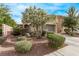 Inviting home exterior featuring a lush flowering tree, a two-car garage, and desert landscaping at 3005 Dotted Wren Ave, North Las Vegas, NV 89084