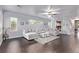 Spacious living room with dark wood floors, a ceiling fan, and a large sectional sofa at 3005 Dotted Wren Ave, North Las Vegas, NV 89084
