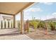 Landscaped backyard featuring a covered patio, brick flooring, gravel, young trees, and privacy plants at 354 Spotted Dove St, Las Vegas, NV 89138