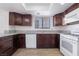 Bright kitchen featuring wood-look tile, granite countertops, white appliances, and dark brown cabinetry at 3937 S Torrey Pines Dr, Las Vegas, NV 89103