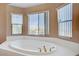 Luxurious bathroom features a large soaking tub with bright windows and neutral color palette at 4012 Owlshead Mountain St, Las Vegas, NV 89129