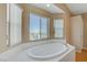 Large bathroom with lots of light, featuring a soaking tub with large windows and neutral color palette at 4012 Owlshead Mountain St, Las Vegas, NV 89129
