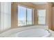 Bathroom features soaking tub with large windows offering a scenic view with neutral color palette at 4012 Owlshead Mountain St, Las Vegas, NV 89129