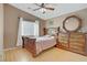 Comfortable bedroom featuring wood laminate flooring, ceiling fan and a dresser with a large mirror at 4012 Owlshead Mountain St, Las Vegas, NV 89129