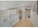Bright hallway with hardwood floors, white railings, and arched wall decor leading to additional rooms at 4012 Owlshead Mountain St, Las Vegas, NV 89129