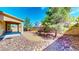 View of the backyard area with a patio, rock landscaping, a block wall, and shade trees at 524 Blanche Ct, Henderson, NV 89052
