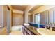 Bright bathroom featuring double sinks, vanity with cabinets, and a tub with tiled enclosure at 524 Blanche Ct, Henderson, NV 89052