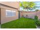 Well-kept backyard with artificial turf, a small seating area, and mature landscaping at 601 Bear Grass St, Las Vegas, NV 89144