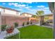 Well-maintained backyard with lush artificial turf, potted flowers, and covered patio at 601 Bear Grass St, Las Vegas, NV 89144