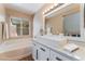 Well-lit bathroom featuring a modern vanity, quartz counters, a tub, and a window for natural light at 601 Bear Grass St, Las Vegas, NV 89144