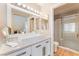 Well-lit bathroom with double vanity, quartz counters, large mirror, and walk-in shower at 601 Bear Grass St, Las Vegas, NV 89144