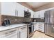 Updated kitchen featuring stainless appliances, granite countertops, white cabinets, and modern backsplash at 601 Bear Grass St, Las Vegas, NV 89144