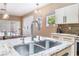 Granite kitchen island with stainless steel sink and gooseneck faucet next to counter with cooktop at 601 Bear Grass St, Las Vegas, NV 89144