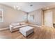 Comfortable living room featuring wood flooring, white couch, ottoman, and white trimmed windows at 601 Bear Grass St, Las Vegas, NV 89144