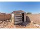 Backyard shot of a simple outdoor storage shed with metal shelving for organization, located in a sunny space at 6489 Coldwater Bay Dr, Las Vegas, NV 89122
