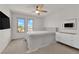 Bright bedroom with a white upholstered bed, ceiling fan, and natural light from two windows at 6643 Tangled Vines Ave, Las Vegas, NV 89139