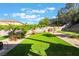 Landscaped backyard featuring artificial grass, a putting green, and a wall of flowering vines for added privacy at 695 Orbiter Ln, Las Vegas, NV 89148