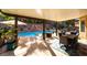 Inviting covered patio overlooking a pool with a waterfall feature, offering a perfect spot for outdoor dining and relaxation at 695 Orbiter Ln, Las Vegas, NV 89148