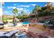 Beautiful backyard pool area with a spa, rock waterfall feature, lounge chairs, and covered patio for outdoor entertaining at 695 Orbiter Ln, Las Vegas, NV 89148