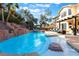 Backyard features a custom pool with rock features, built-in bar, and spacious lounge area at 695 Orbiter Ln, Las Vegas, NV 89148