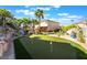 Spacious backyard with a putting green and a pool area surrounded by palm trees, ideal for outdoor recreation and relaxation at 695 Orbiter Ln, Las Vegas, NV 89148