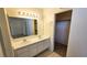 Well-lit bathroom featuring a double sink vanity, neutral tile flooring, and an adjacent walk-in closet for storage at 7053 Magic Moment Ln, Las Vegas, NV 89119