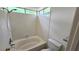 Cozy bathroom featuring a tub with shower, white tile surround, and a window letting in natural light at 7053 Magic Moment Ln, Las Vegas, NV 89119