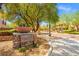 Inviting Cascade entrance featuring stone signage, desert landscaping, and mature shade trees along the paved street at 7931 Campers Village Ave, Las Vegas, NV 89178
