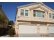 Beige two-story townhome featuring a multi-car garage and well-maintained landscaping at 9343 Leaping Deer Pl # 103, Las Vegas, NV 89178