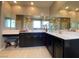 Bathroom with double sinks, tiled floors, large mirrors, and dark cabinets with white countertops at 10152 Tenaya Meadows St, Las Vegas, NV 89178