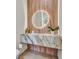 Modern powder room featuring a marble sink, wood paneling, and a round lighted mirror at 10528 Garden Light Dr, Las Vegas, NV 89135