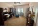 This bedroom has neutral carpet, a ceiling fan, a window with shutters, a desk, and bookcases at 10561 Rancho Destino Rd, Las Vegas, NV 89183