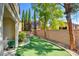 The backyard features artificial turf, mature trees, and a well-maintained brick wall providing privacy at 11833 Amistoso Ln, Las Vegas, NV 89138