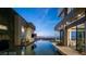 Side view of luxurious backyard featuring infinity pool, outdoor seating, bar and city views at dusk at 1491 Reims Dr, Henderson, NV 89012