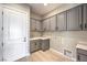 A bright laundry room features gray cabinetry and a stainless steel sink at 2194 Pigeon Hawk St, Las Vegas, NV 89138
