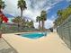 Community pool surrounded by a patio, mature palm trees, and decorative red flowers under a partly cloudy sky at 2471 Old Forge Ln # 103, Las Vegas, NV 89121