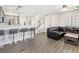 Open-concept living room with gray laminate flooring, kitchen bar, and a comfortable leather sofa at 4014 Sparrow Rock St, Las Vegas, NV 89129