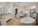 Bright bathroom featuring a modern tub, dual vanities, and walk-in closet, all on light wood floors at 4574 Fiore Bella Blvd, Las Vegas, NV 89135