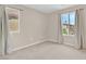 Empty bedroom featuring neutral walls, carpeted floors, and two bright windows with curtains at 4992 W Moberly Ave, Las Vegas, NV 89139