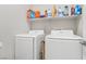 Bright laundry room with shelving above modern, white washer and dryer units at 5220 Remini Ct, Las Vegas, NV 89130