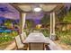 Elegant outdoor dining area under a pergola, surrounded by lush greenery and ambient lighting at 62 Grand Masters Dr, Las Vegas, NV 89141